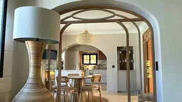 Un intérieur comprenant un coin repas, un grand vase et une cuisine en arrière-plan.