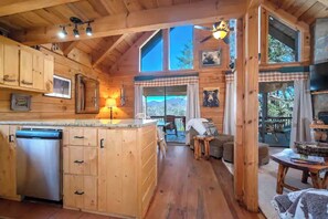 Ein Holzblockhaus-Interieur mit Küche, Essbereich und einem großen Fenster mit Blick auf eine schöne Landschaft.