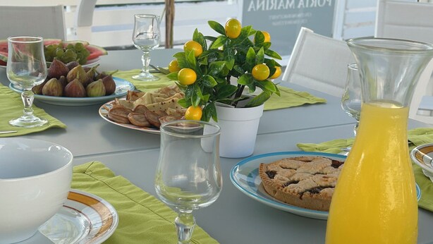 A table set for breakfast with plates of food, a pitcher of juice, and a potted plant. - Porta Marina Resort Pompeii (Pompei)