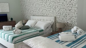 A hotel room with two beds, a television, a lamp, and a wall with a leaf pattern. - Porta Marina Resort Pompeii (Pompei)