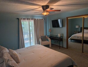 A bedroom with a bed, desk, chair, TV, and a large mirror. - ON THE ISLAND (Holiday Island)