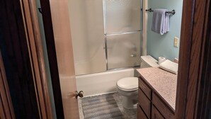 Ein Badezimmer mit Duschkabine, Toilette und Waschbecken mit Ablagefläche.
