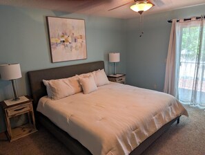 Ein Schlafzimmer mit einem großen Bett, zwei Nachttischen, einem Deckenventilator und einem Fenster mit Vorhängen.