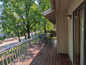 A wooden deck with a railing, a table, and chairs. - ON THE ISLAND (Holiday Island)