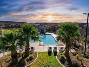 A rectangular swimming pool surrounded by palm trees and lounge chairs, with a view of residential buildings in the background. - Top Southern Utah Adventures | Pool + Spa (Washington)