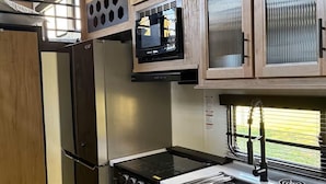 A compact kitchen with a refrigerator, stove, microwave, and sink.