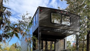 A mobile home with a metal exterior, a window, and a ladder.