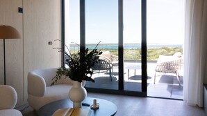 Ein modernes Zimmer mit einer großen Schiebeglas-Tür, die auf einen Balkon mit Sitzmöbeln führt.
