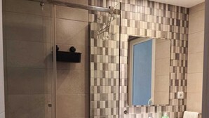 Un bany modern amb plat de dutxa de vidre, resclosa de rajola, un lavabo amb mirall i un vàter.