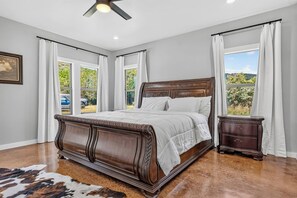 Ein Schlafzimmer mit einem großen Bett, einem Nachttisch und einem Deckenventilator.