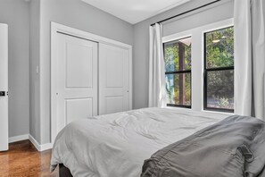 Un dormitorio con cama, ventana con cortinas y una puerta.