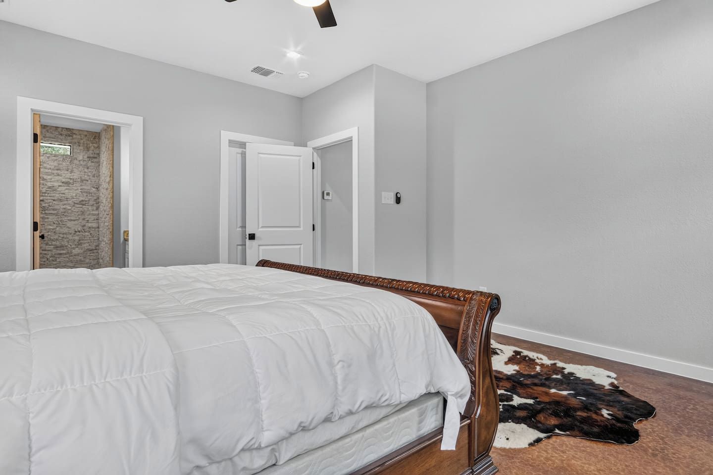 Un dormitorio con una cama grande, una puerta que da a un baño y una pared de piedra.