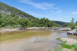 Eine natürliche Landschaft mit Fluss, felsigem Gelände und üppiger Vegetation.