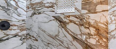 A wall with a marble pattern, a black faucet, and a small window with a geometric pattern.