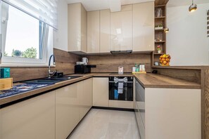A modern kitchen with a window, wooden countertop, and built-in appliances. - Villa ADRIA MOMENTS with private pool (Pinezići)