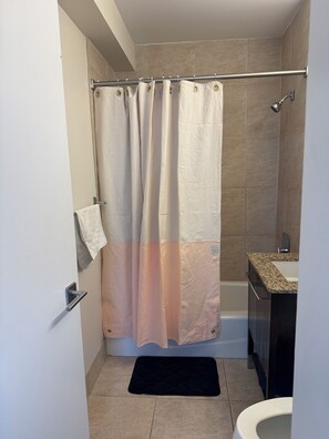 Ein Badezimmer mit Duschvorhang, Handtuchhalter, Waschbecken und Toilette.