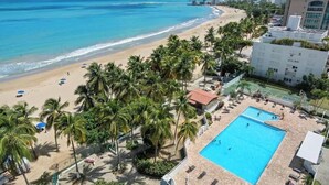 Ein Hotel direkt am Strand mit Swimmingpool, Palmen und Meerblick.