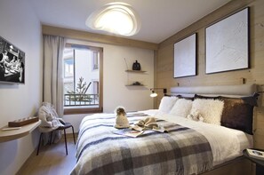 A hotel room with a bed, a desk, a chair, a window, and artwork on the walls. - 10m from ski slopes, fitness, swimming pool, sauna, hammam, tv, ski locker, 52m², Alpe d'Huez (Huez)