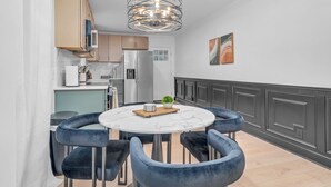 Una cucina moderna con un tavolo rotondo in marmo, sedie blu scuro e una lampada a sospensione originale.