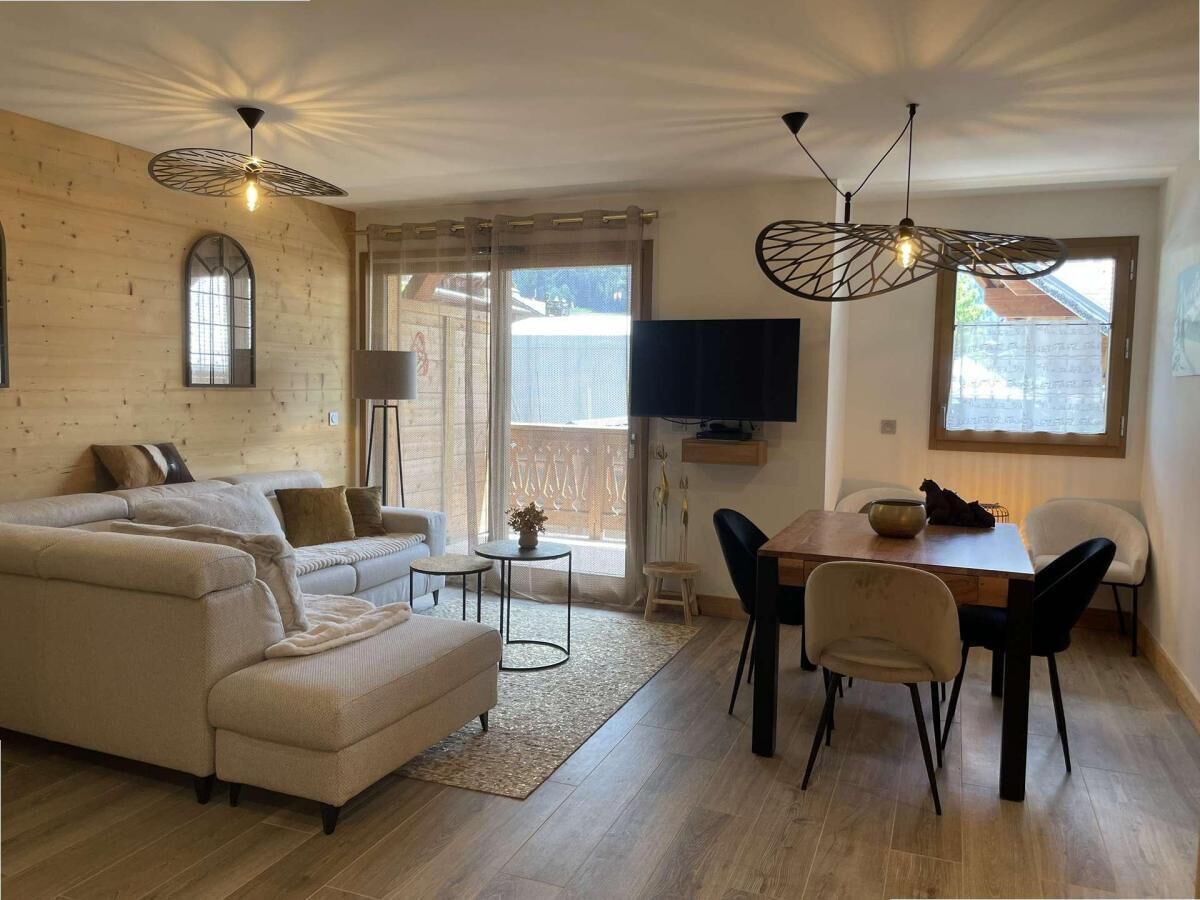 Un salon avec un canapé, une table à manger et des chaises, un téléviseur et une fenêtre.