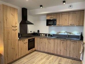 A modern kitchen with wooden cabinetry, a built-in oven, a microwave, and a stainless steel sink. - 140m from ski lifts, 1st floor, terrace, tv, 62m², Morzine (Morzine)