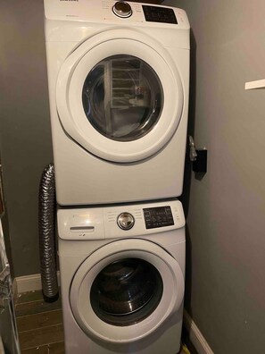Eine übereinander gestellte Waschmaschine und ein Trockner in einem Waschraum.