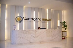 A reception desk with a marble top, a logo with a circular emblem, and the words 'Cartagena BEACH Exclusive Resort Residences' on the wall behind it. - Ocean View Suite in Cartagena 🌊 Pool • Beach • Airport in Crespo (Cartagena de Indias)
