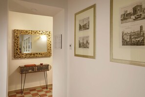 Ein Flur mit einem dekorativen Spiegel, Schwarz-Weiß-Fotos in Rahmen und einem Konsolentisch mit Musterdesign.