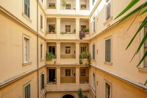 Ein mehrgeschossiges Gebäude mit Balkonen, Blumentöpfen und einem zentralen Innenhof.