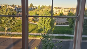 Vista a través de una ventana con cielo despejado, una calle y edificios residenciales.