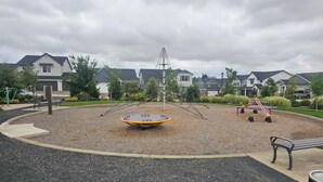 Un parque infantil con tobogán, sube y baja y una superficie de caucho circular.