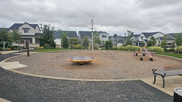 Une aire de jeux équipée d’une balançoire, d’un jeu à bascule et d’une surface circulaire en caoutchouc.