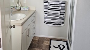 Un baño con un lavamanos blanco, una toalla a rayas y una alfombra con el número 8.