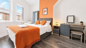Ein Schlafzimmer mit Bett, Schreibtisch, Stuhl, Nachttisch und Fenster.