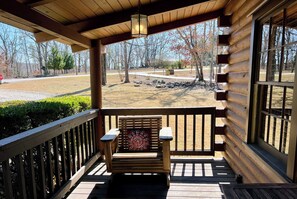 A wooden deck with a bench and a lantern, overlooking a park with trees and a road. - The Roosevelt - Close to Mountainside pool! (Warm Springs)