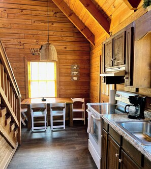 A wooden cabin-style kitchen with a wooden ceiling, a hanging light fixture, a window, a stove, and a sink. - The Roosevelt - Close to Mountainside pool! (Warm Springs)