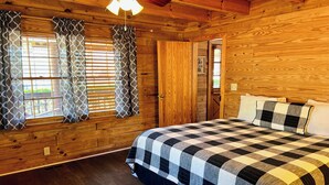 Een houten kamer met een bed, gordijnen en een plafondventilator.