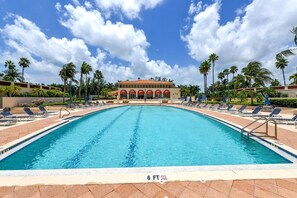 A swimming pool with lounge chairs and umbrellas, a building with red arches, and palm trees. - Luxury Rental in Bay Isles facing the Bay (Longboat Key)