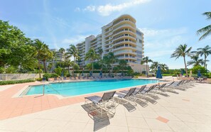 Ein Hotel mit Schwimmbad, Liegestühlen und Palmen.