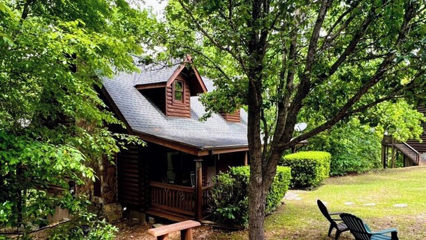 Eine Hütte mit Veranda, einer Bank und einem Baum im Vordergrund.