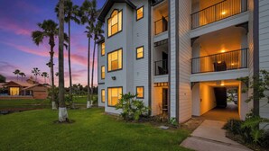 A multi-story residential building with balconies, a covered entryway, and a well-maintained lawn. - Lakeside view retreat at Villas del Sol (Kissimmee)