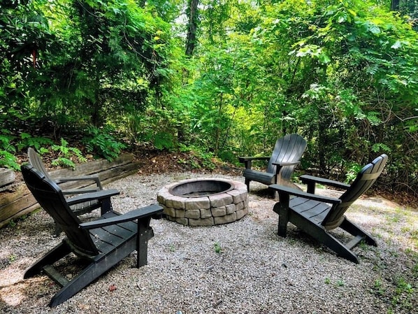 An outdoor seating area with Adirondack chairs and a stone fire pit surrounded by gravel. - Beautiful sunsets, decks, firepit! (Warm Springs)