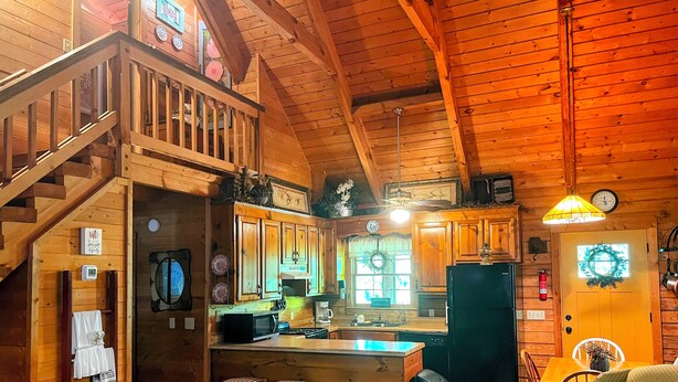 Ein Holzblockhaus-Interieur mit Küche, Essbereich und einer Treppe.