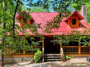 A rustic cabin with a red roof, wooden porch, and a staircase leading to the entrance. - Shabby Chic meets the mountains! Sleeps 6 (Warm Springs)