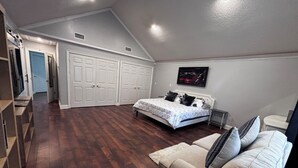 Ein Schlafzimmer mit Bett, einer Couch, einer weißen Tür und einem Flur, der in einen anderen Raum führt.
