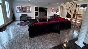 Ein Wohnzimmer mit einer Couch, einem Sessel, einem Fernseher und einer Treppe.