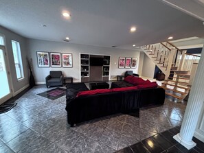 Ein Wohnzimmer mit einer Couch, einem Sessel, einem Fernseher und einer Treppe.