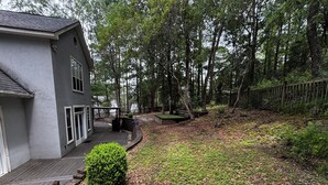 Ein Wohnhaus mit überdachter Terrasse, kleinem Garten und Holzzaun.