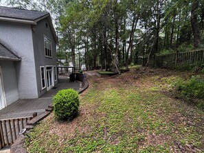 Ein Wohnhaus mit überdachter Terrasse, kleinem Garten und Holzzaun.