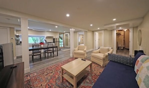 A spacious living area with a sofa, armchairs, a coffee table, and a dining area with a table and chairs.